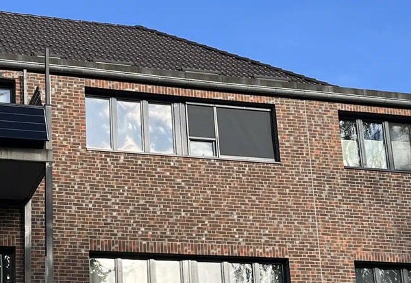 Una persiana enrollable en la fachada de un edificio residencial protege las ventanas de la luz solar directa.